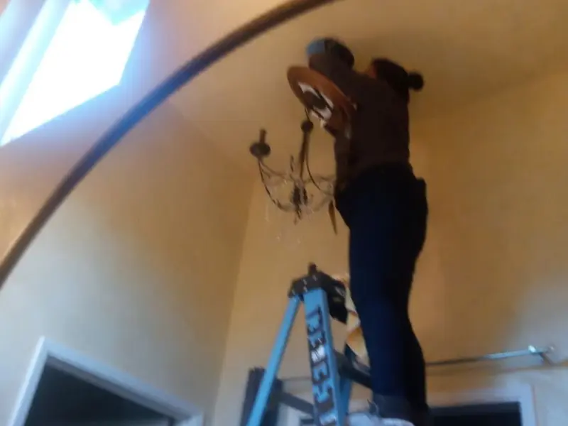 Electrician installing a chandelier in a South Houston residence